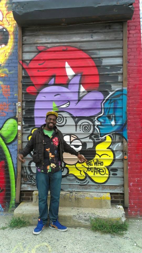 Tripoli standing in front of a 'Be Who You Are' mural