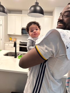 Tripoli holding a baby in the kitchen