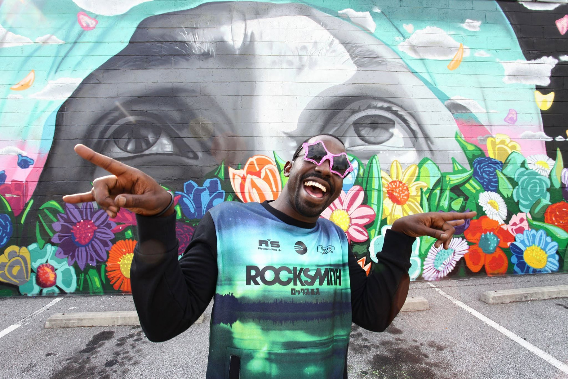 Tripoli laughing in front of a flower mural in Atlanta